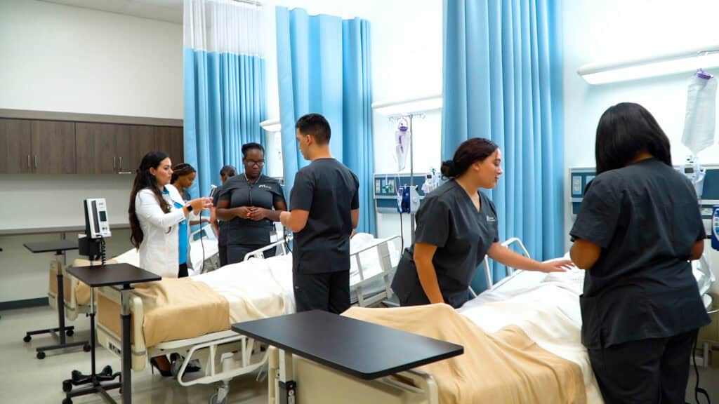 Miramar ASN nursing school students are practicing in an FVI skills lab under the supervision of a member of the nursing faculty