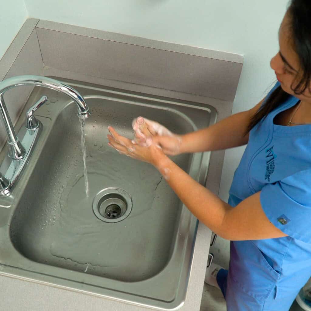 A Miami patient care tech program student practices proper handwashing at a sink
