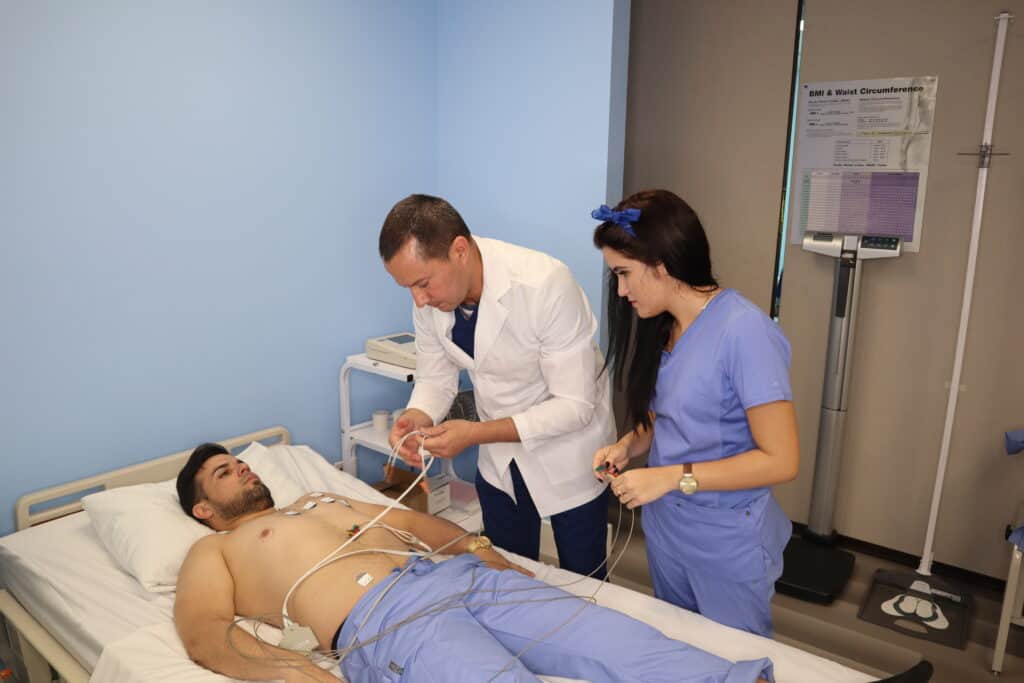 Two Students practice hands-on under the supervision of an instructor in a skills lab