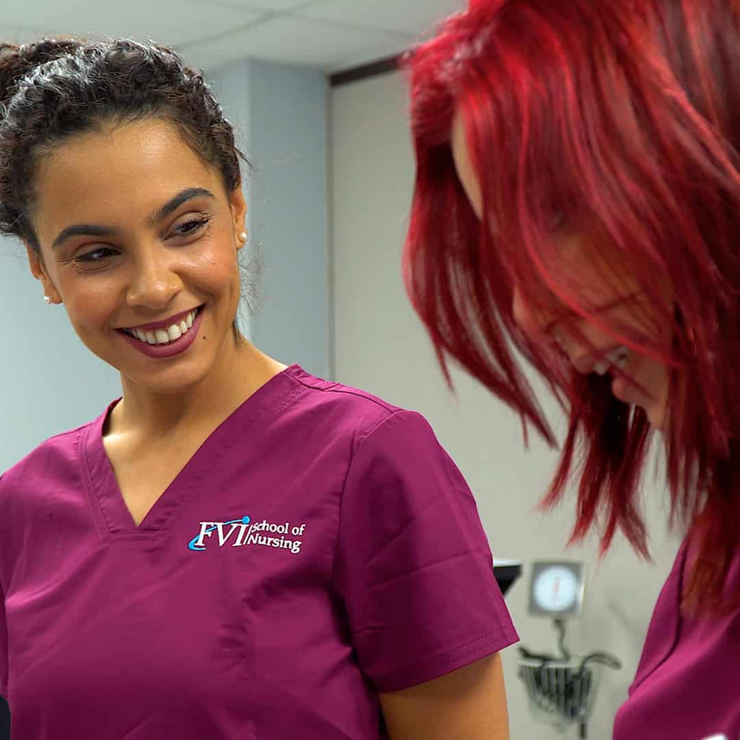 Practical Nursing student at FVI smiling while receiving guidance from her instructor during clinical practice.