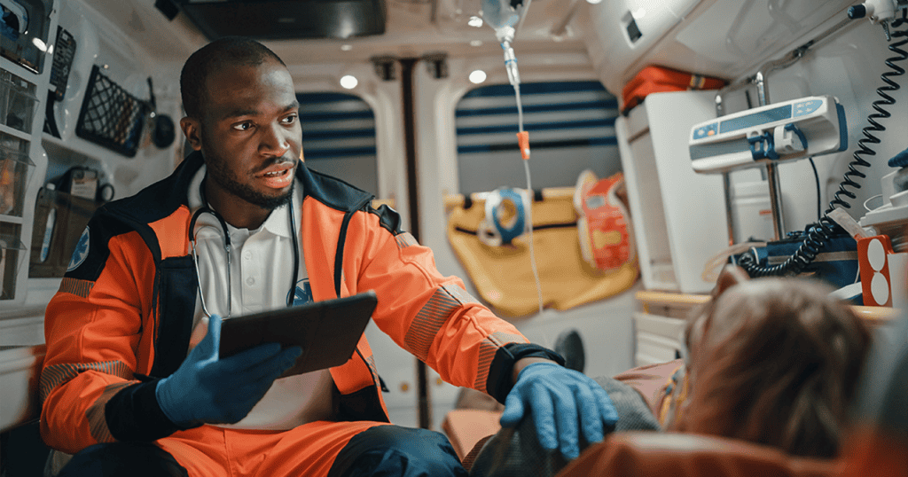 EMT reviewing patient data on a tablet inside ambulance. EMT training program includes technology driven care