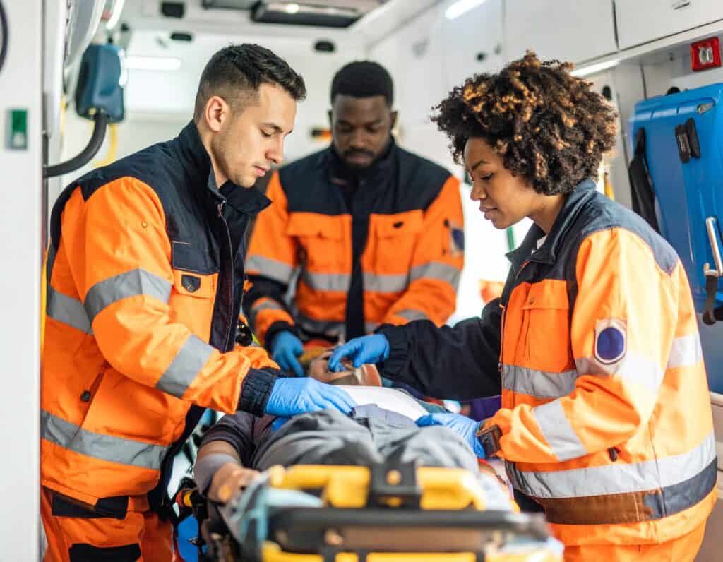 EMT team providing emergency care to a patient inside an ambulance.